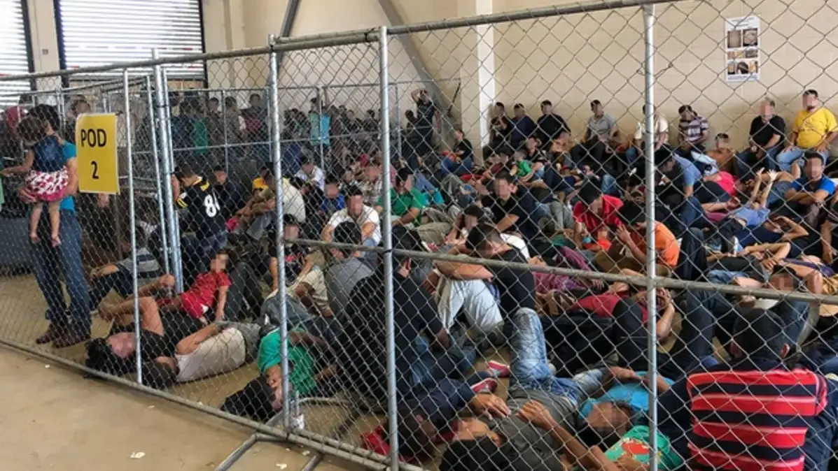 Migrantes detenidos sentados en el suelo dentro de una instalación de detención migratoria en Estados Unidos, contexto de deportaciones y salida voluntaria.