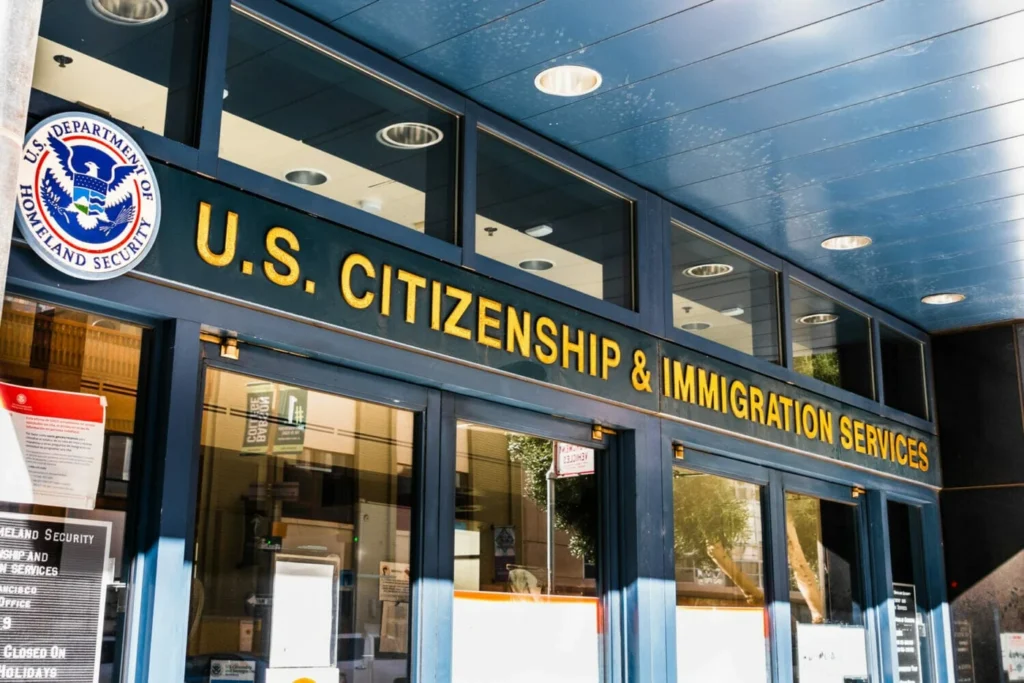 Aumento de tarifas USCIS 2026: fachada de una oficina de USCIS con el letrero “U.S. Citizenship and Immigration Services” en la entrada.